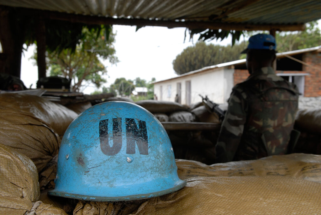 Image of a UN Indian peacekeeper unit position in North Kivu province in eastern Democratic Republic of Congo in the background, with a close-up UN blue peacekeeper's helmet. This image is used to illustrate the launch of a new open online course on safeguarding children in peacekeeping.
