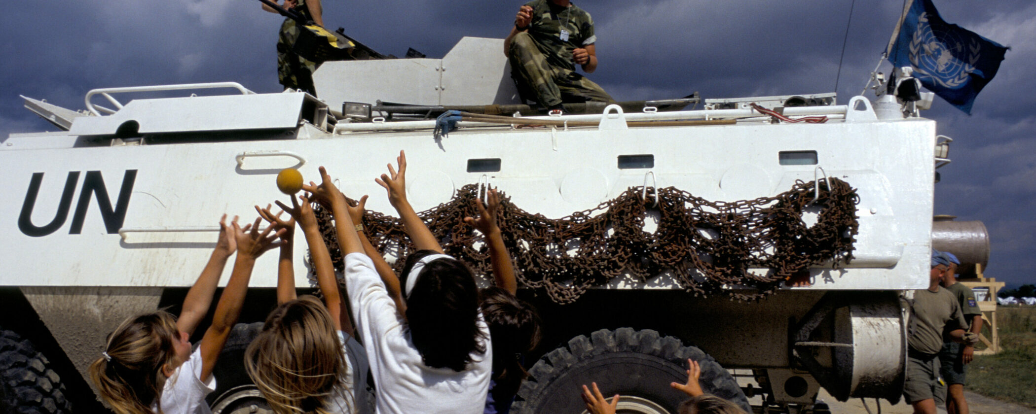 Refugee children from Srebrenica play ball with UN soldiers at Tuzla airbase in July 1995