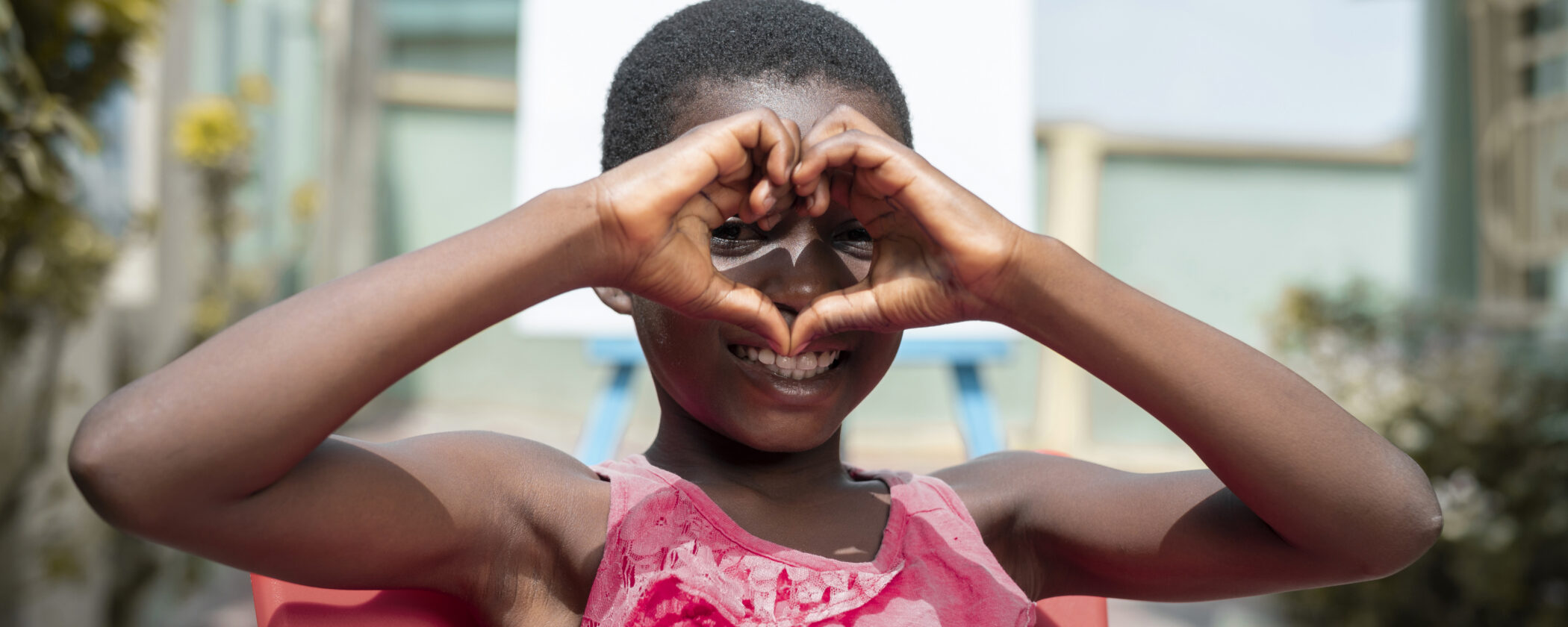 smiley kid making a heart hand