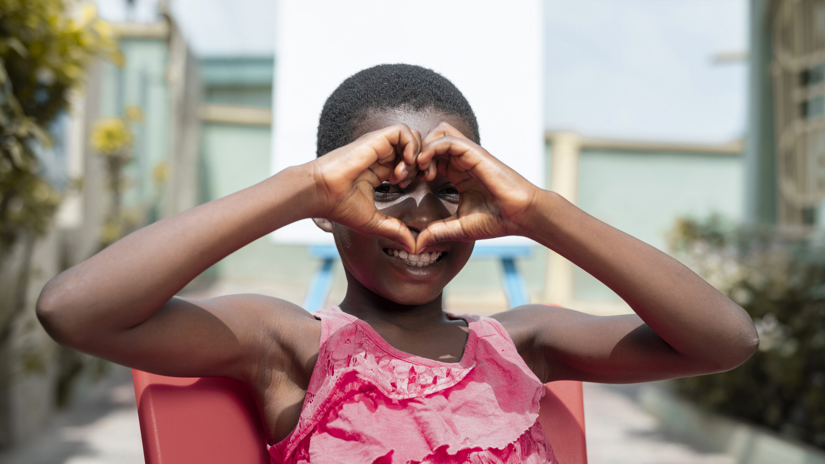 smiley kid making a heart hand